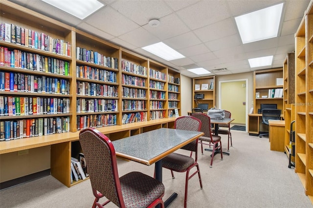 office featuring built in shelves, a paneled ceiling, and light carpet