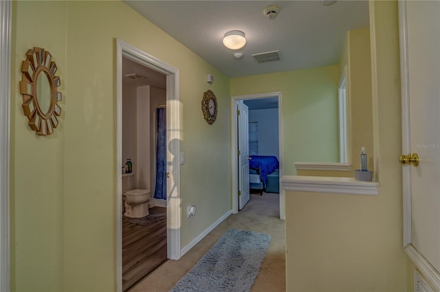 hallway featuring light carpet and a textured ceiling