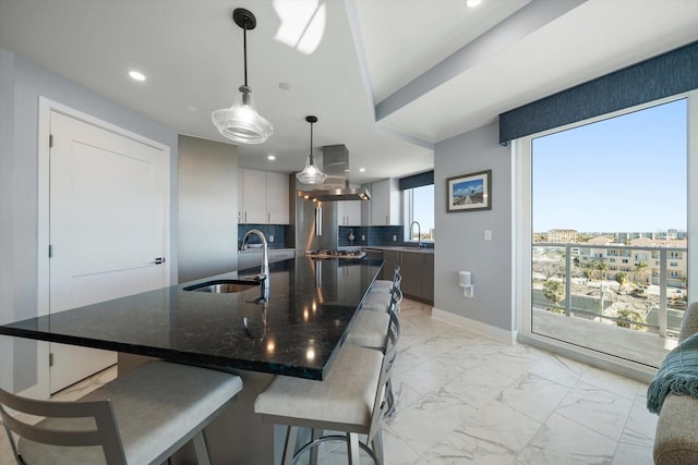 kitchen featuring island exhaust hood, backsplash, decorative light fixtures, and sink