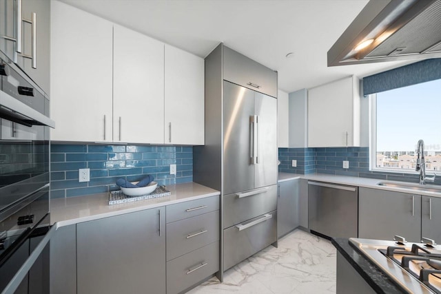 kitchen featuring decorative backsplash, stainless steel appliances, gray cabinets, and sink