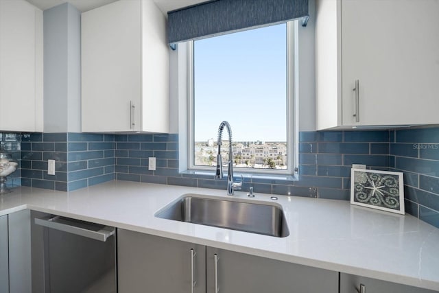 kitchen with tasteful backsplash, dishwasher, sink, and white cabinets