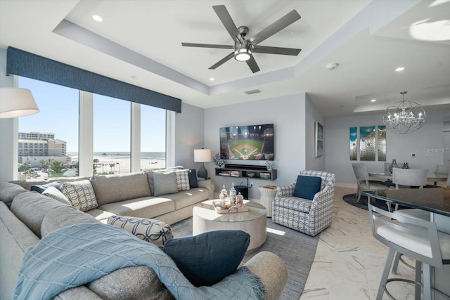 living room with a raised ceiling and ceiling fan with notable chandelier