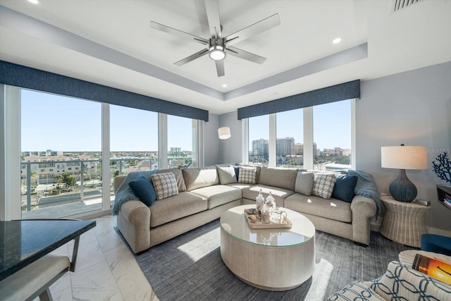 living room with ceiling fan and a tray ceiling