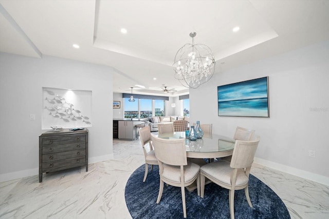 dining area with ceiling fan and a tray ceiling