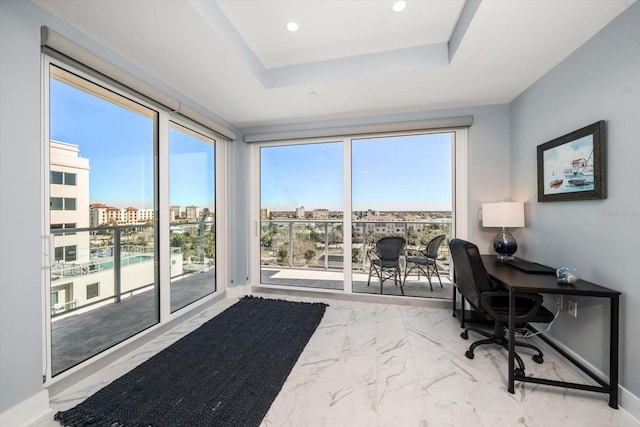 home office featuring a tray ceiling and a healthy amount of sunlight