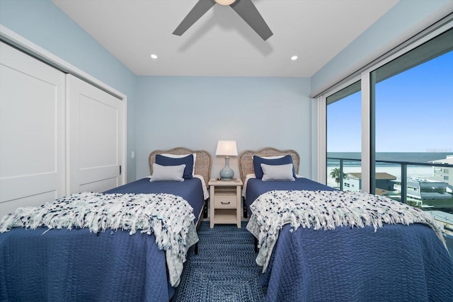 carpeted bedroom featuring ceiling fan, a closet, and a water view