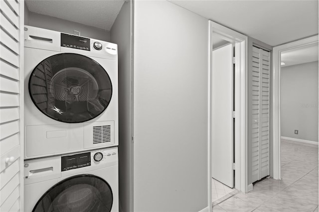 laundry area featuring stacked washer / dryer and a textured ceiling