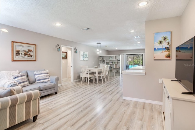 living room with a textured ceiling and light wood-type flooring