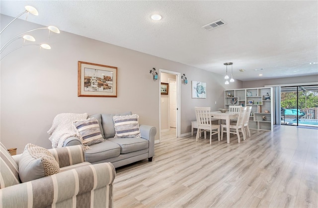 living room with a textured ceiling and light hardwood / wood-style flooring