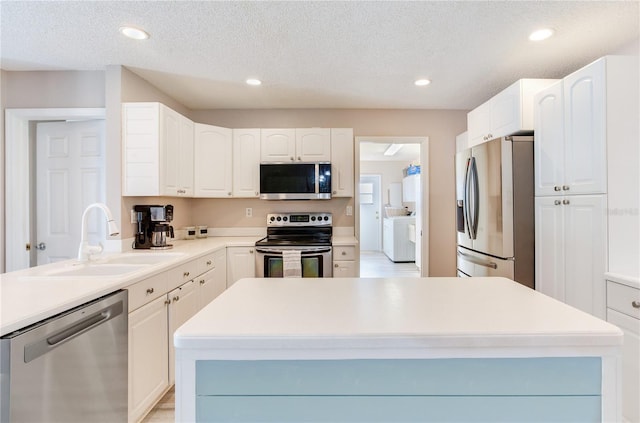 kitchen featuring white cabinets, a center island, stainless steel appliances, and sink