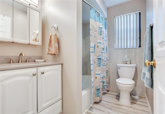 full bathroom with tile walls, wood-type flooring, toilet, vanity, and shower / tub combo