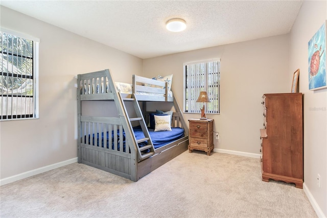 bedroom featuring multiple windows, carpet, and a textured ceiling