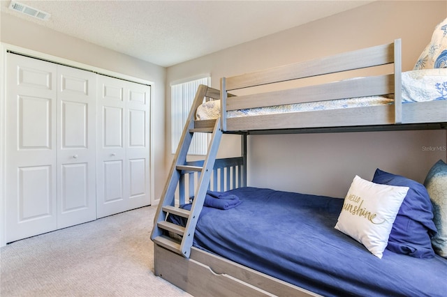 bedroom featuring a textured ceiling, light carpet, and a closet