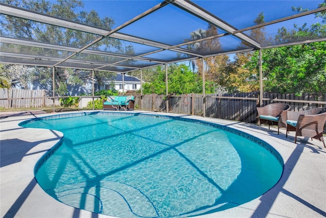 view of pool with glass enclosure and a patio