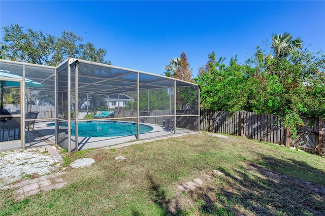 view of pool with glass enclosure and a lawn