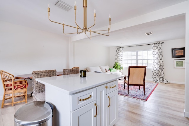 kitchen featuring white cabinetry, a center island, a notable chandelier, and light wood-type flooring