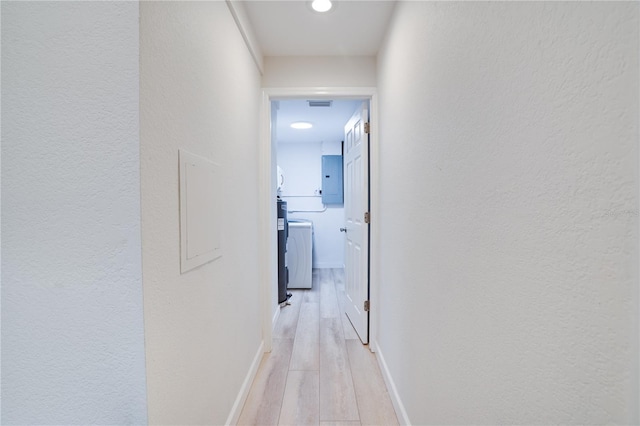 corridor featuring electric panel, light hardwood / wood-style floors, and washer and clothes dryer