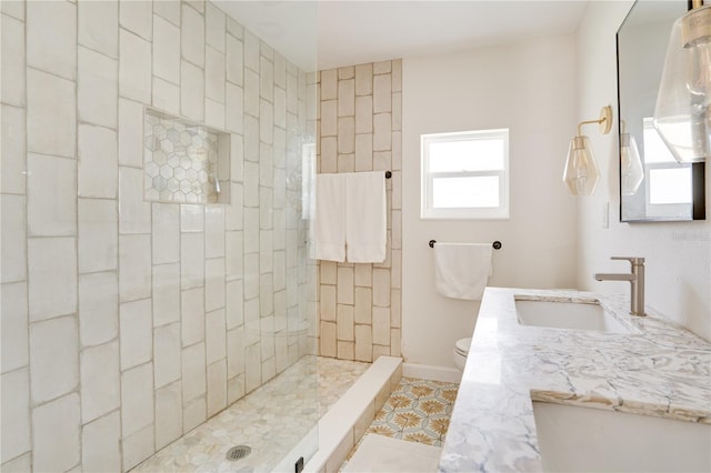 bathroom with vanity, toilet, and a tile shower