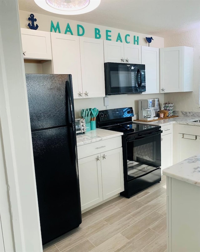 kitchen featuring black appliances, white cabinets, light stone counters, and light hardwood / wood-style flooring