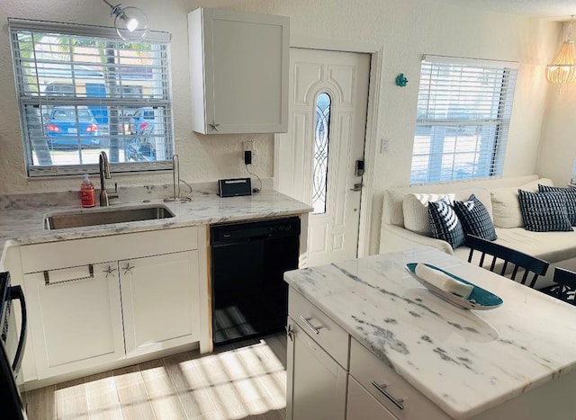 kitchen featuring white cabinets, sink, light stone countertops, and black dishwasher