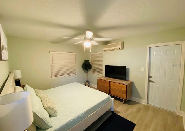 bedroom with ceiling fan, light wood-type flooring, and a wall unit AC