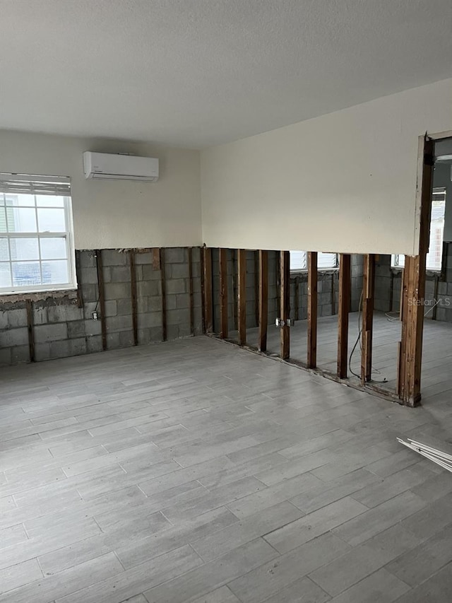 basement featuring light hardwood / wood-style floors and a wall mounted AC