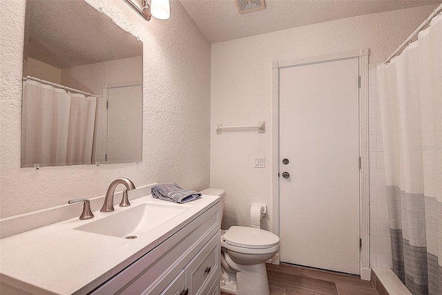 bathroom with vanity, a shower with curtain, hardwood / wood-style flooring, toilet, and a textured ceiling