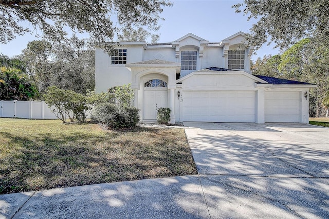 mediterranean / spanish-style house featuring a front yard, fence, an attached garage, stucco siding, and concrete driveway