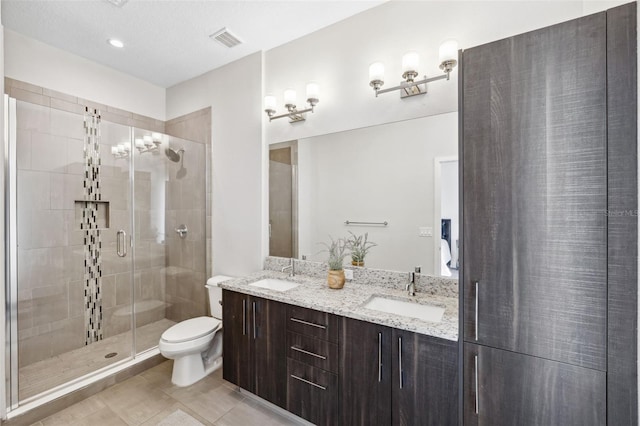 bathroom with tile patterned floors, vanity, toilet, and a shower with shower door