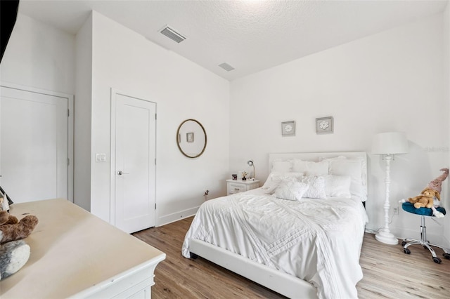 bedroom with light hardwood / wood-style flooring and a textured ceiling