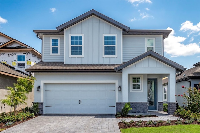 7849 Somersworth Dr, Kissimmee, FL 34747 - view of front facade with board and batten siding, decorative driveway, stone siding, a garage, and a shingled roof