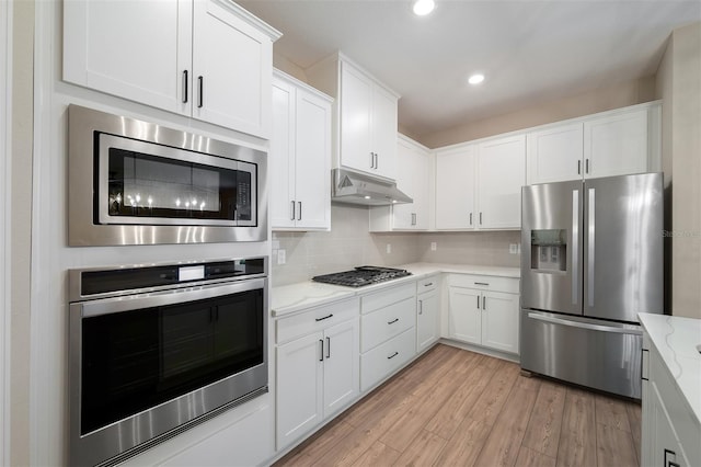 kitchen featuring light stone counters, white cabinetry, stainless steel appliances, and light hardwood / wood-style flooring