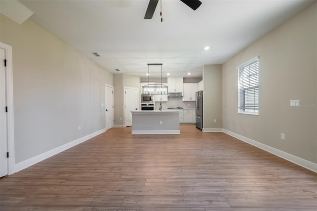 kitchen featuring a kitchen island, light hardwood / wood-style floors, hanging light fixtures, and appliances with stainless steel finishes