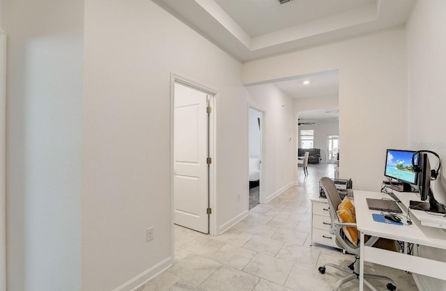 tiled office space with a raised ceiling and ceiling fan