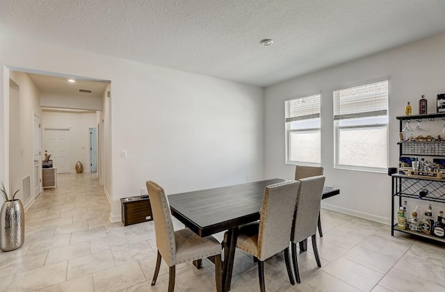 tiled dining space with a textured ceiling