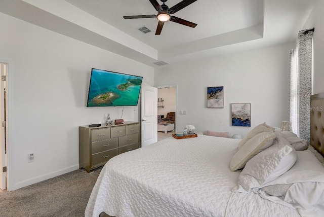 carpeted bedroom with ceiling fan and a raised ceiling