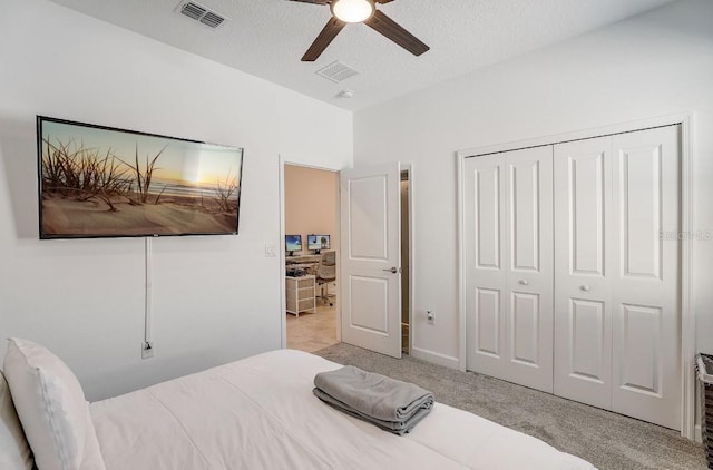 carpeted bedroom with ceiling fan, a textured ceiling, and a closet