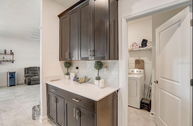 bar featuring decorative backsplash, dark brown cabinetry, ceiling fan, washer / dryer, and wine cooler