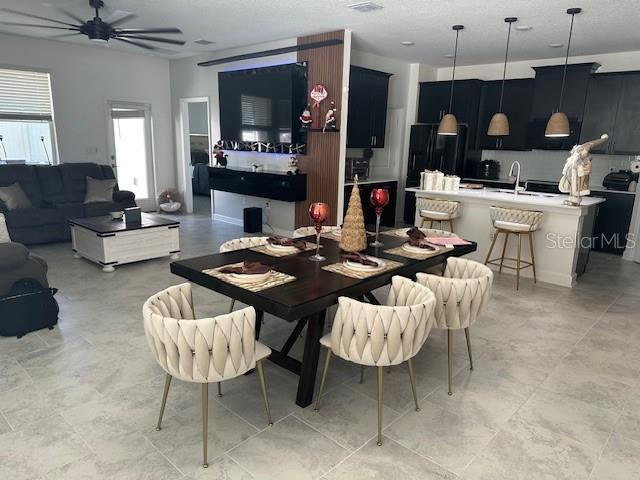 dining area with ceiling fan and sink