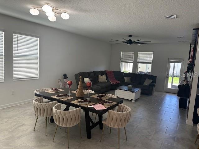 dining area with a textured ceiling, ceiling fan, and a healthy amount of sunlight