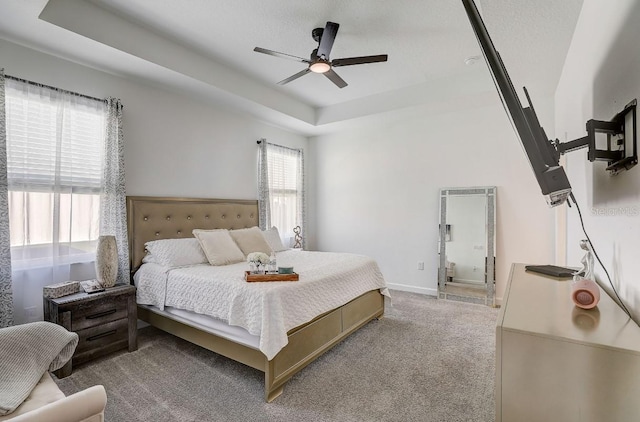 bedroom with ceiling fan, a raised ceiling, light colored carpet, and a textured ceiling