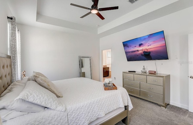 bedroom featuring ceiling fan, a raised ceiling, and light colored carpet