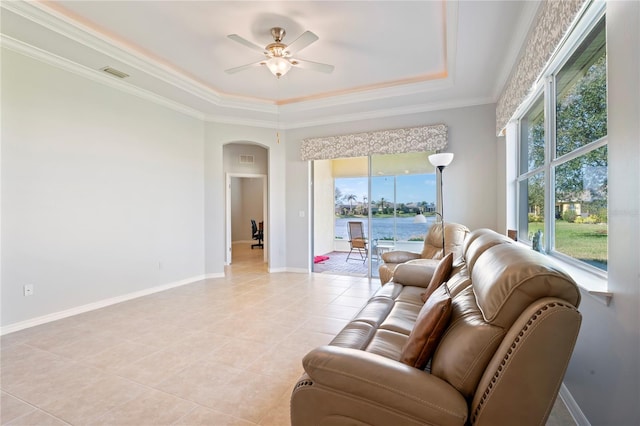 tiled living room with a tray ceiling, ceiling fan, and ornamental molding