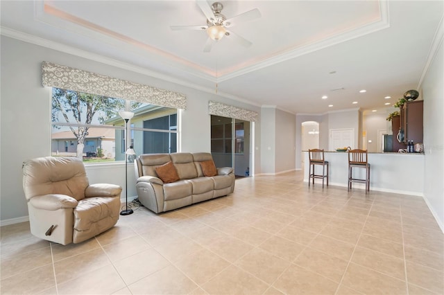 living room with ceiling fan, a raised ceiling, and ornamental molding