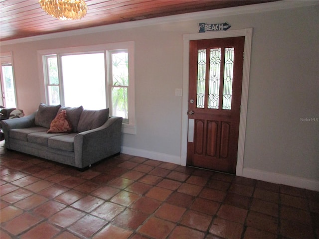 entrance foyer with a chandelier, dark tile patterned floors, ornamental molding, and wood ceiling