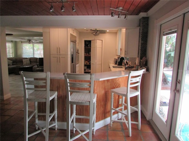 kitchen featuring a kitchen bar, a wealth of natural light, ceiling fan, and wood ceiling