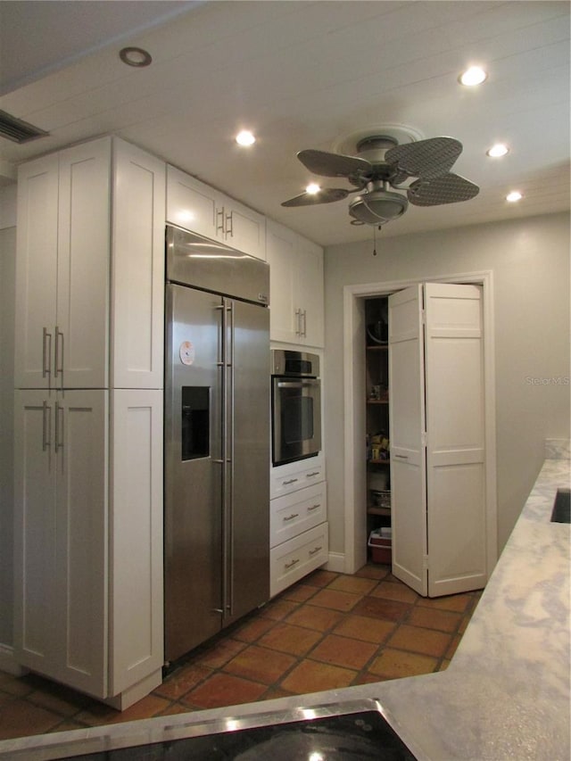 kitchen with ceiling fan, white cabinets, stainless steel appliances, and dark tile patterned flooring