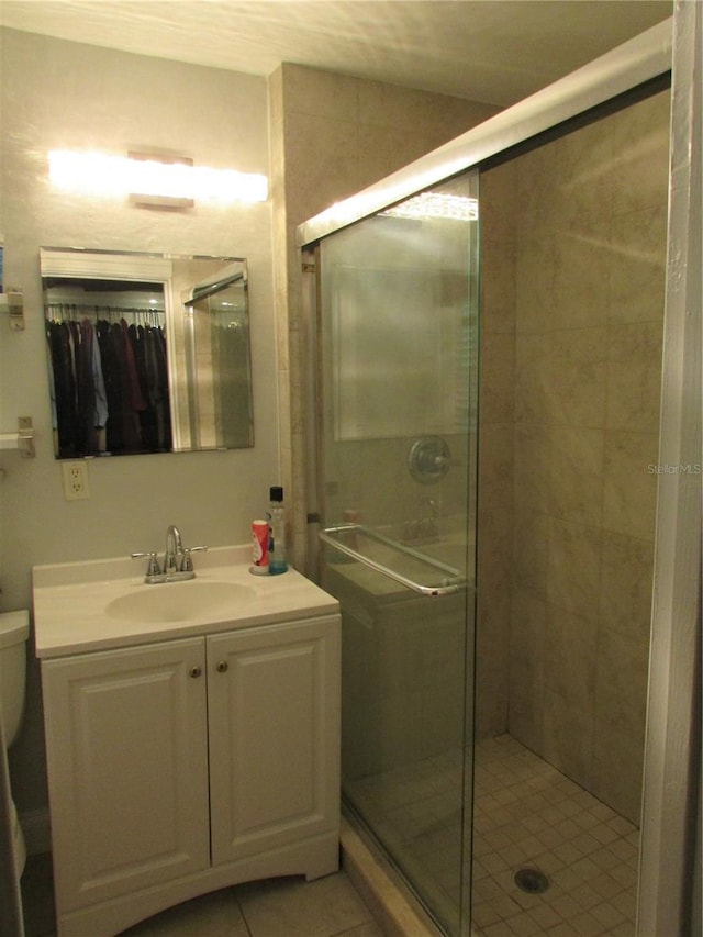 bathroom with tile patterned floors, vanity, toilet, and an enclosed shower