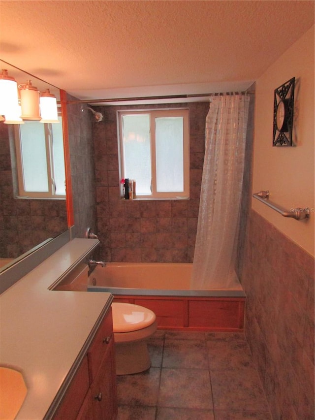 full bathroom featuring tile patterned floors, shower / bath combo with shower curtain, vanity, and a textured ceiling