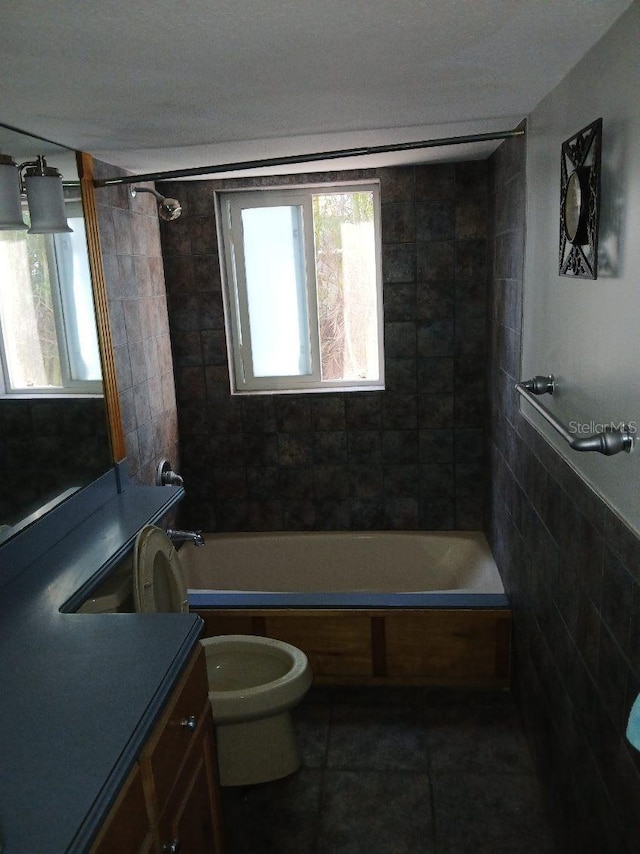 full bathroom featuring vanity, tiled shower / bath, tile patterned flooring, toilet, and tile walls